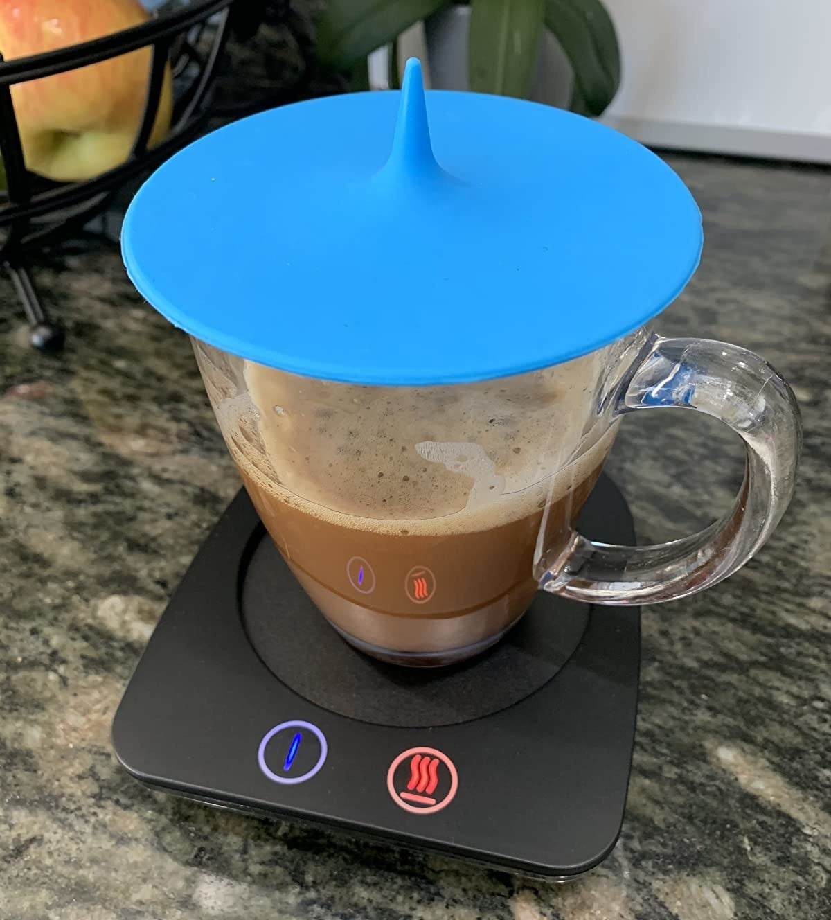 reviewer photo showing coffee mug on a mug warmer with a blue silicone lid cover on top of their mug 