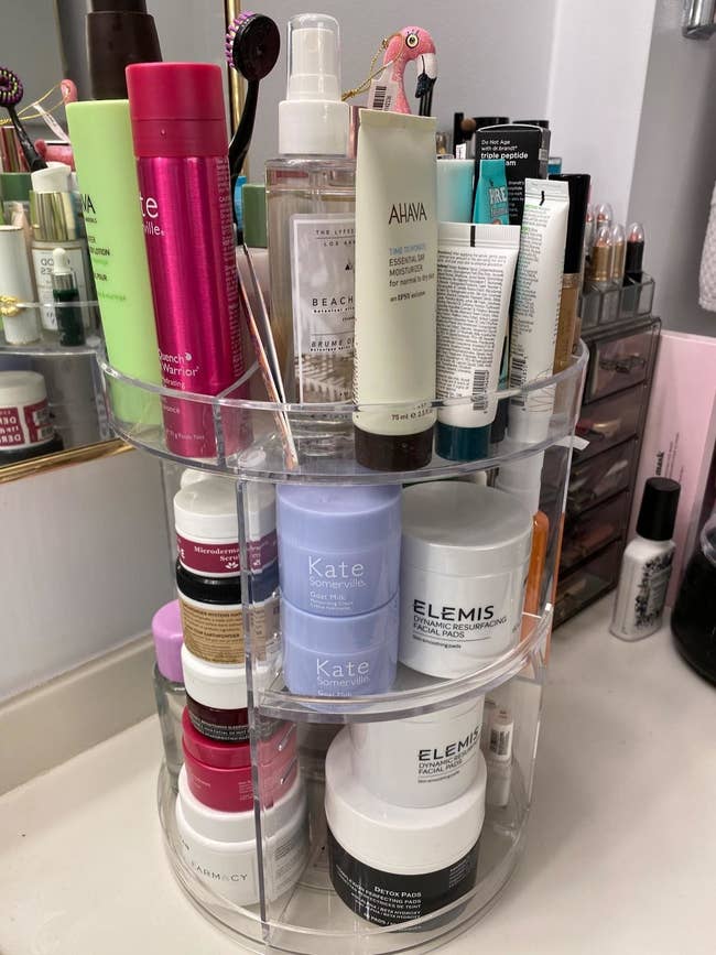 A reviewer's photo of the three-tier rotating organizer holding various skin, face, and hair products