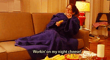 A person in a blanket on a couch saying &quot;working on my night cheese&quot;