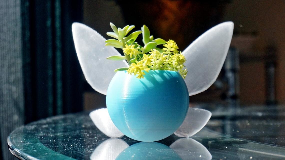 a round blue planter with fairy wings