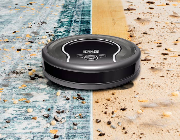 shark robot vacuum cleaning up debris on the floor over a rug and hardwood floor