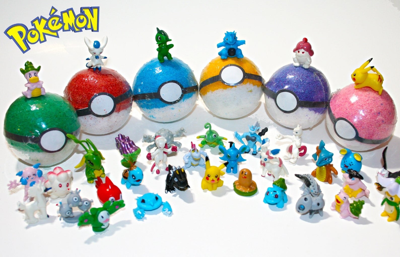 six differently colored bath bombs with an array of tiny pokemon toys around them