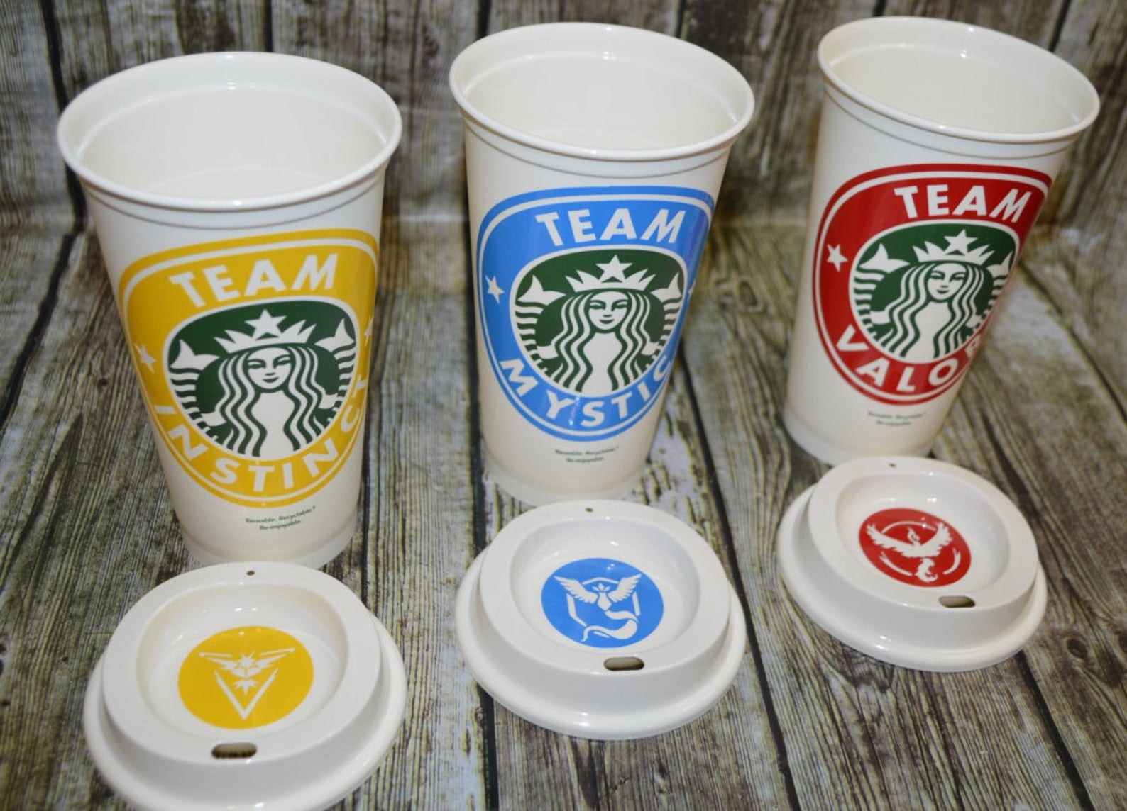 three white hot coffee cups with different pokemon teams and colors on each one