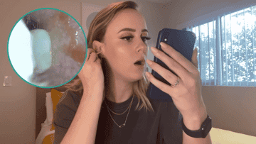 A tester uses the ear cleaning camera tool while watching it on her phone.