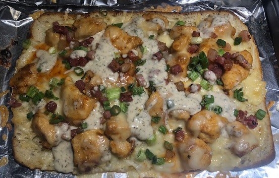 Rectangular flatbread covered in chicken, cheese, pancetta, onions, and ranch