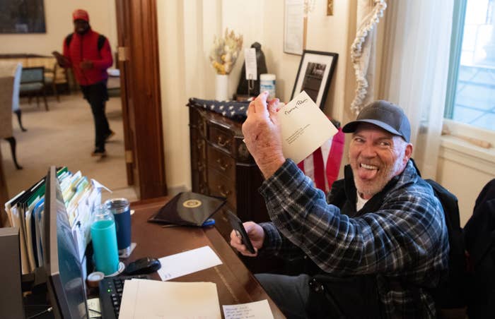Barnett looks straight at the camera and sticks out his tongue, holding up Pelosi's envelope