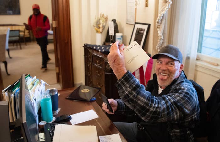 Barnett looks straight at the camera and sticks out his tongue, holding up Pelosi&#x27;s envelope