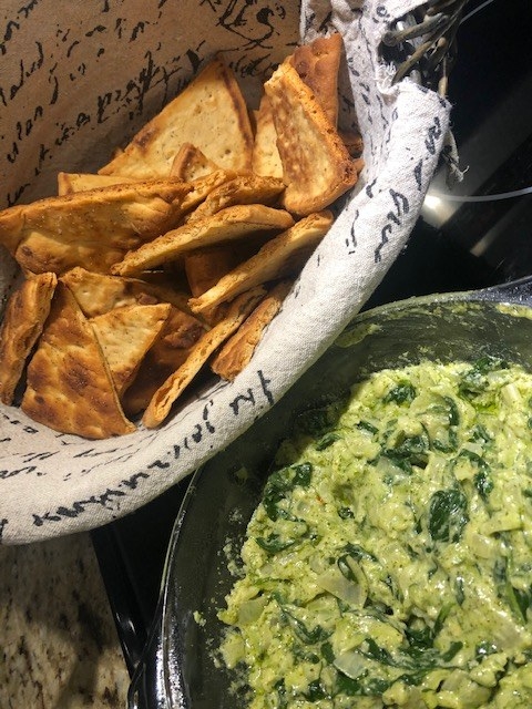 Bowl of pesto spinach dip and a basket of pita chips