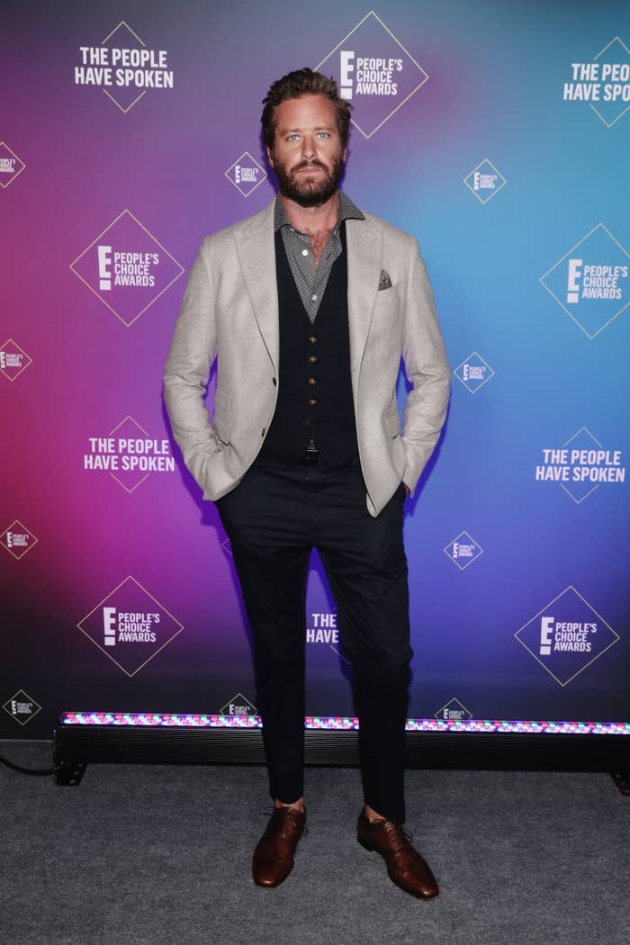 Armie Hammer wears a gray jacket, blue vest, grey patterned button-down, blue slacks, and brown shoes at the 2020 E! People&#x27;s Choice Awards on November 15, 2020