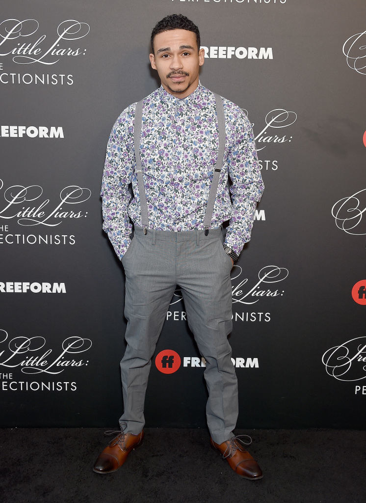 Noah Gray-Cabey attends the &quot;Pretty Little Liars: The Perfectionists&quot; Premiere wearing slacks, a floral-print dress shirt, and. suspenders