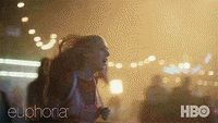 A woman runs to her friend in a crowded carnival at night.