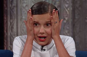 A shocked Millie Bobby Brown grabs her face in horror