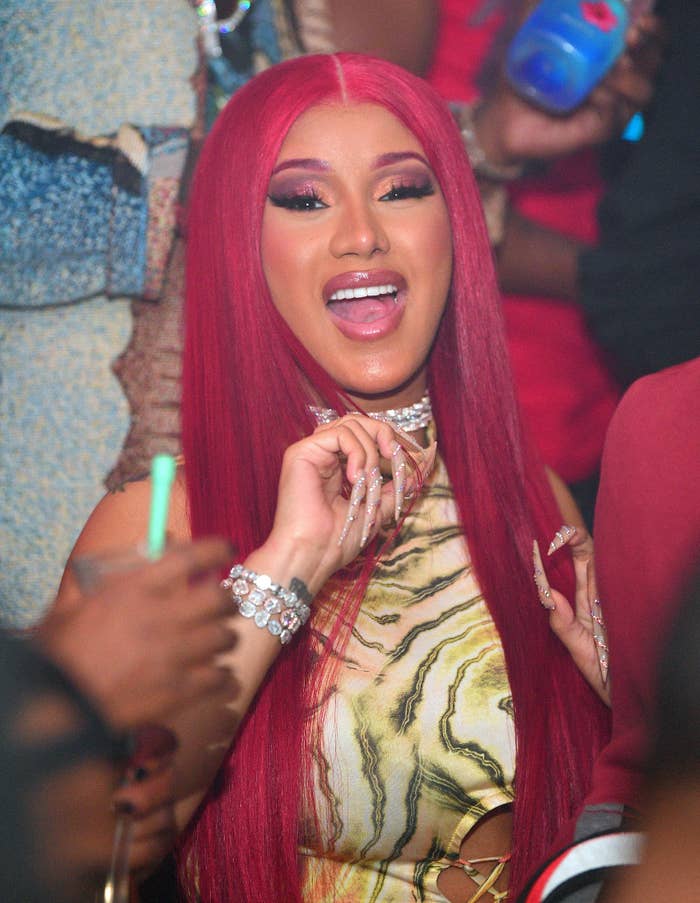 Cardi B with red hair and a striped dress at a club