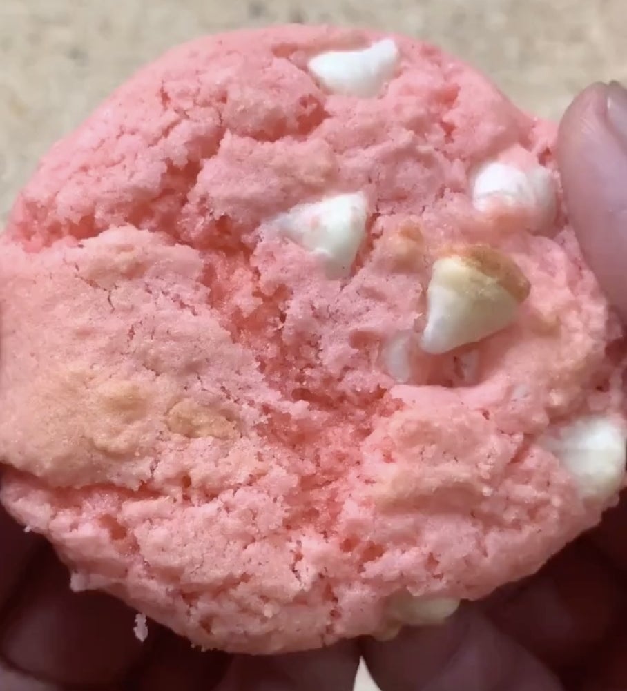 A pink cookie with white chocolate chips