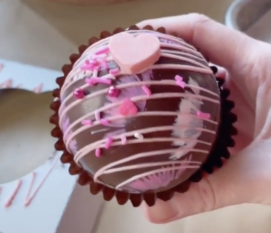 A chocolate sphere with sprinkles and pink chocolate drizzled on top