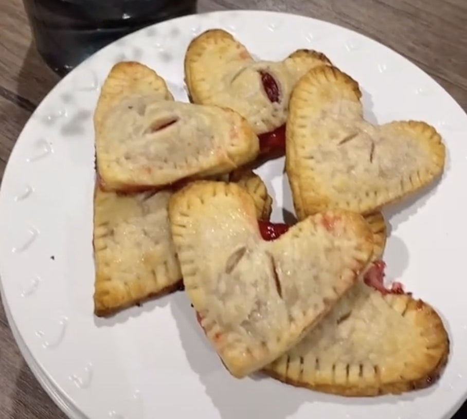 A plate of heart shaped pastries filled with red jam