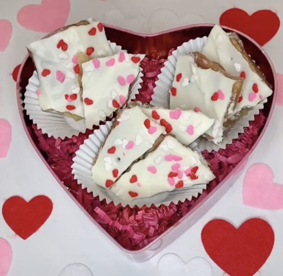 A tin filled with white chocolate pieces with pink heart spinkles