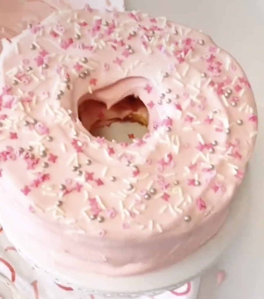 Angel food cake covered in pink frosting and sprinkles