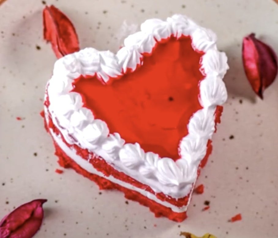 A red heart cake with white frosting in between layers