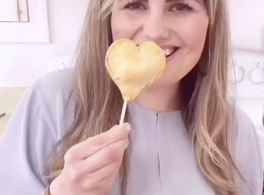 A woman holds a heart shaped pastry on a stick