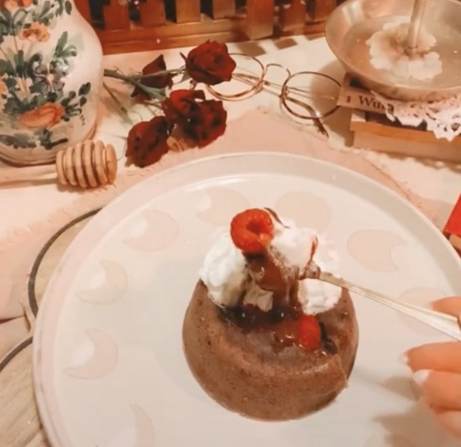 A small round chocolate cake topped with whipped cream and raspberries