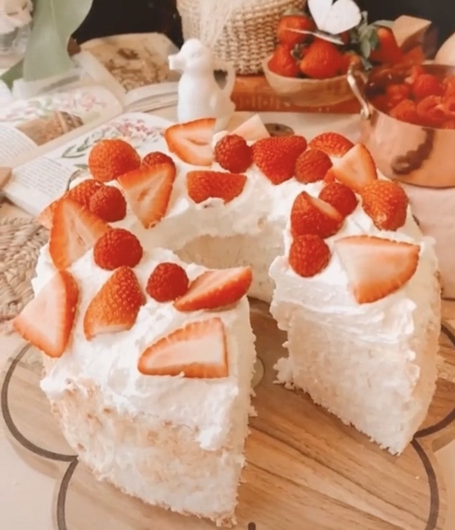An angel food cake topped with strawberries with a slice cut out