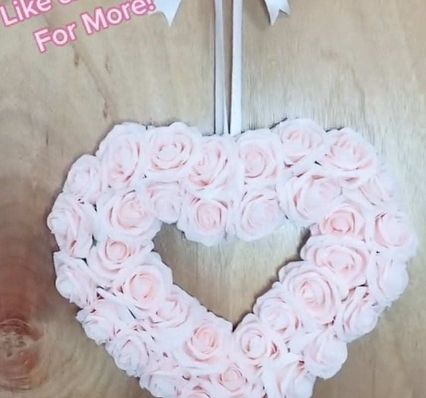 A heart shaped wreath filled with pink roses 