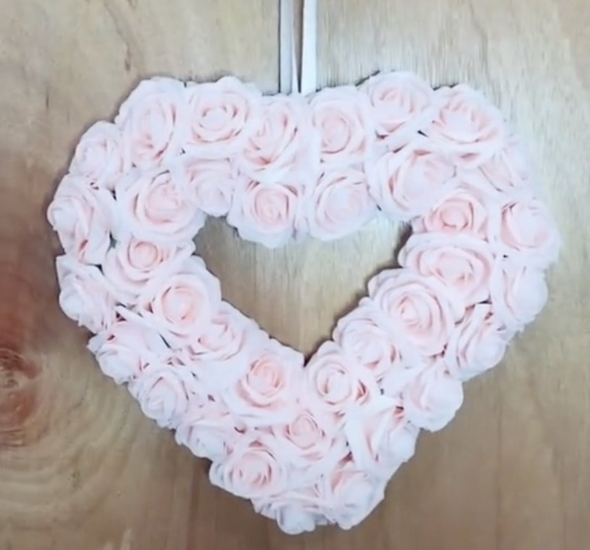 A heart shaped wreath filled with pink roses 