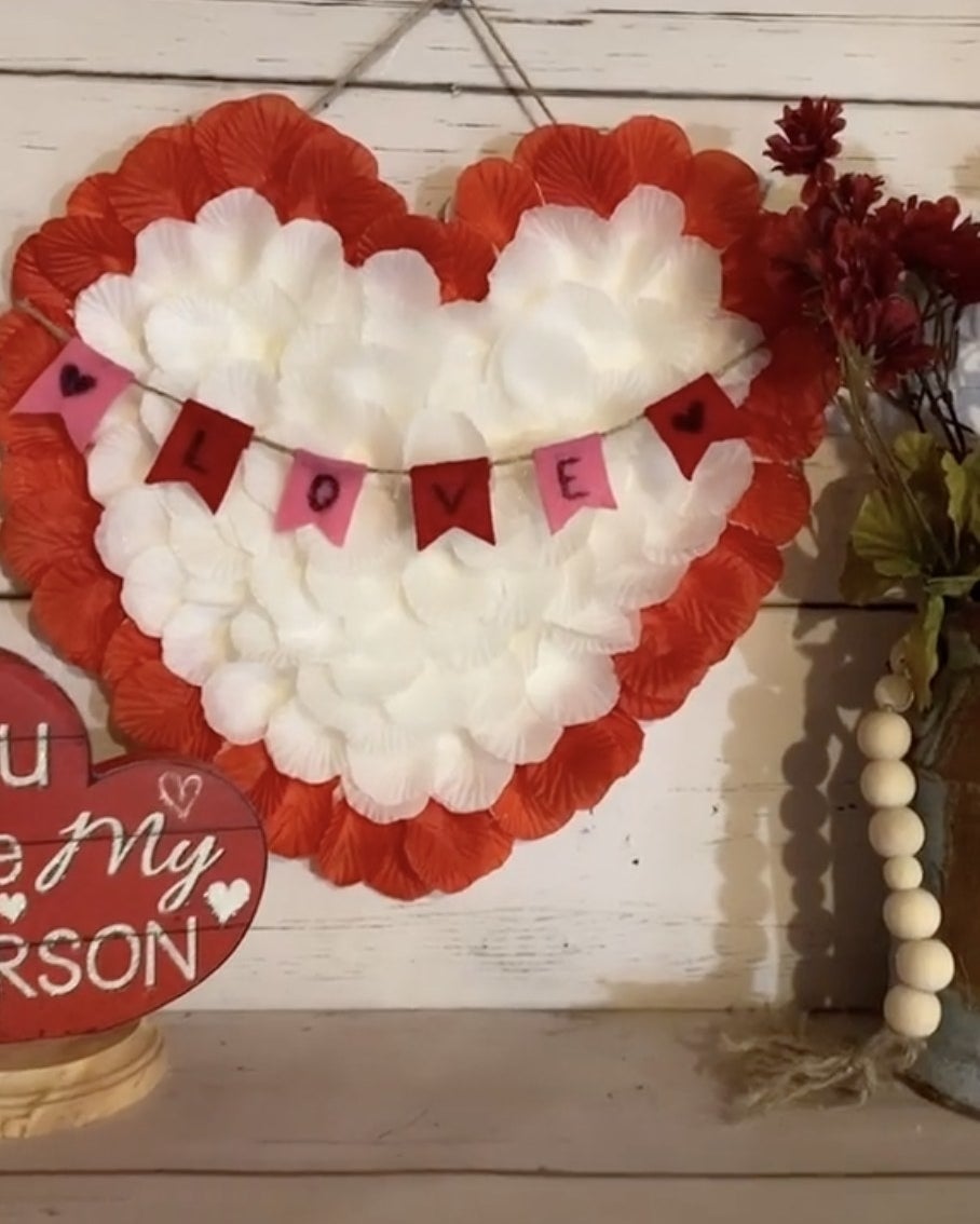 A hanging heart sign covered in red and white flower petals