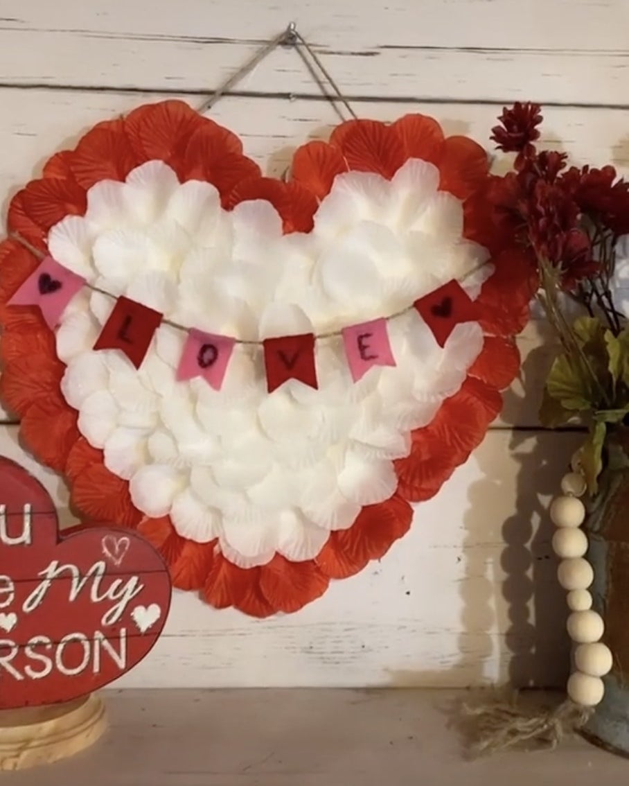 A hanging heart sign covered in red and white flower petals