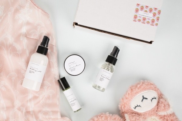 three perfumes and a pair of pink fuzzy slippers and other wellness items 