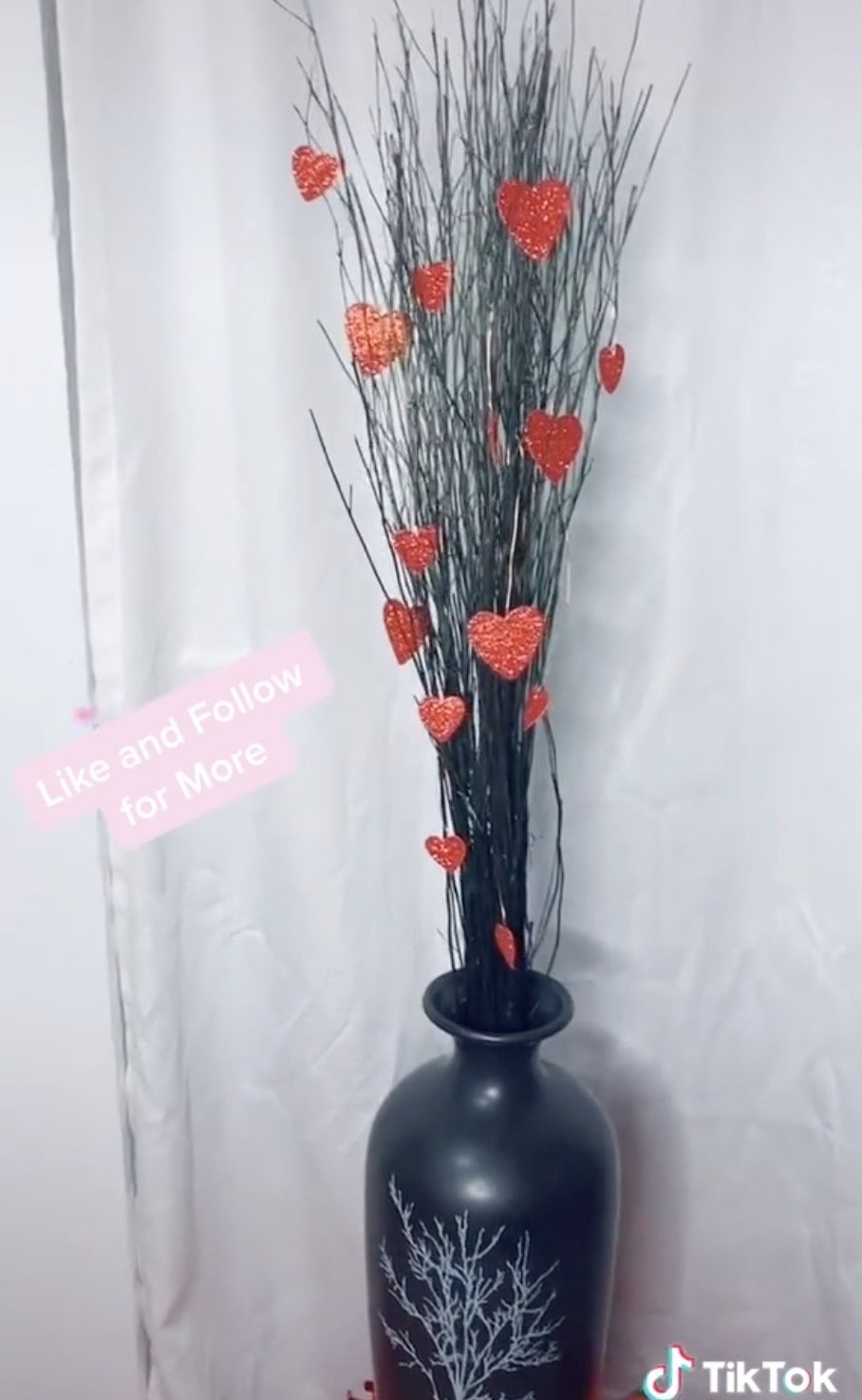 A black vase filled with decorative sticks and hearts