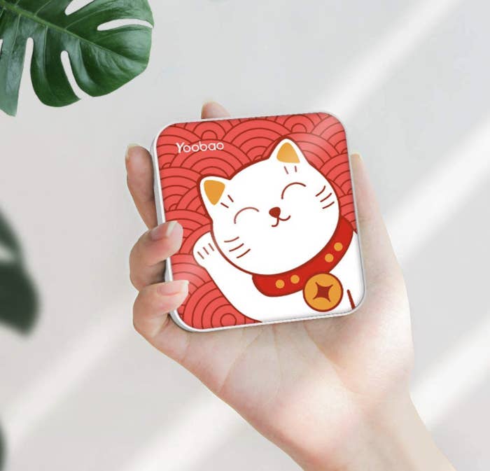 person holding lucky cat power bank