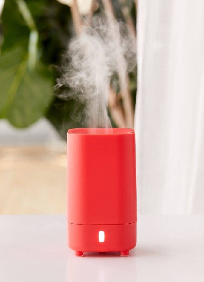 Red essential oil diffuser on top of a white table