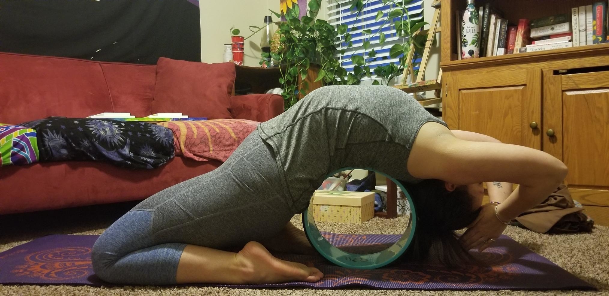 A reviewer using the yoga wheel to stretch their back