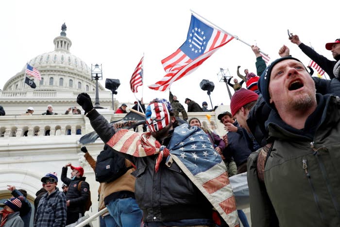 Rioters with American flags and at least one containing the Three Percenters symbol outside the Capitol