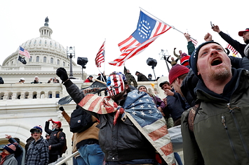Rioters with American flags and at least one containing the three percenter's symbol outisde the Capitol
