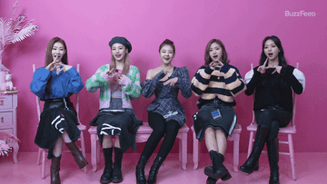 The members of ITZY waving and making their signature hand sign