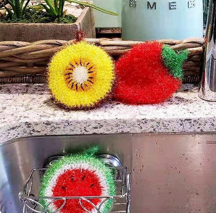 three hand crocheted fruit dish scrubbers by a kitchen sink