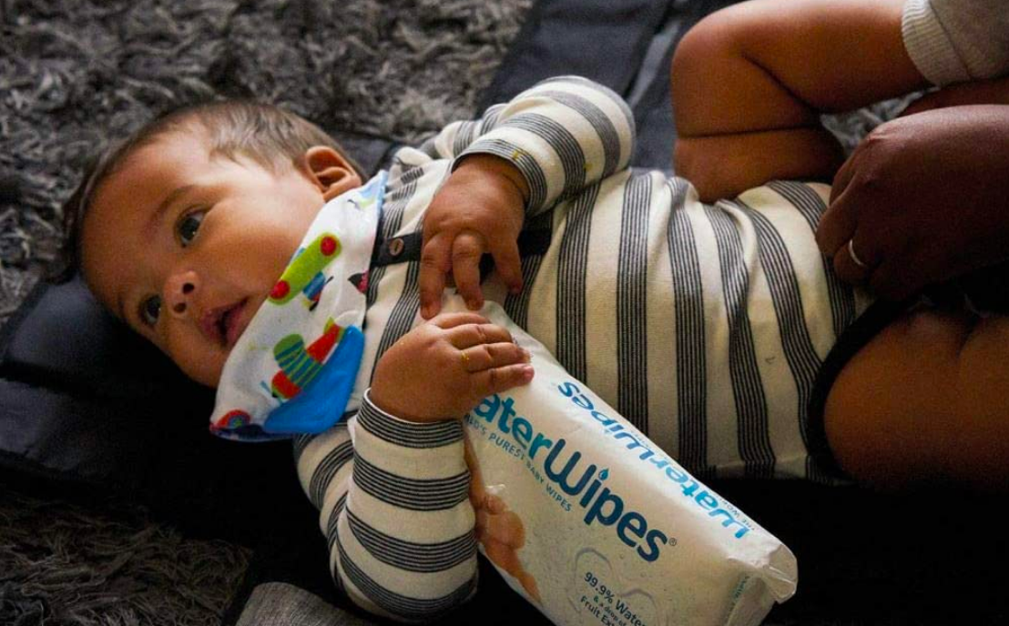 Baby holding bag of diaper wipes 
