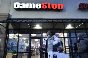 A man wearing a face mask leaves a Game Stop store with the a PlayStation box