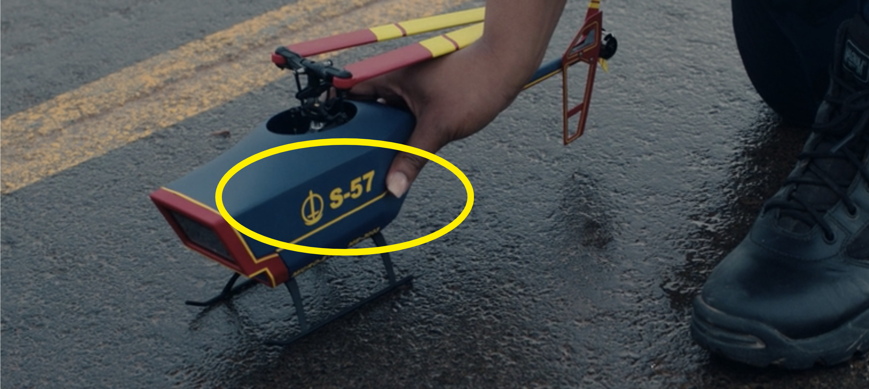 Monica placing a red, blue, and yellow drone on the ground that reads, &quot;S-57&quot;