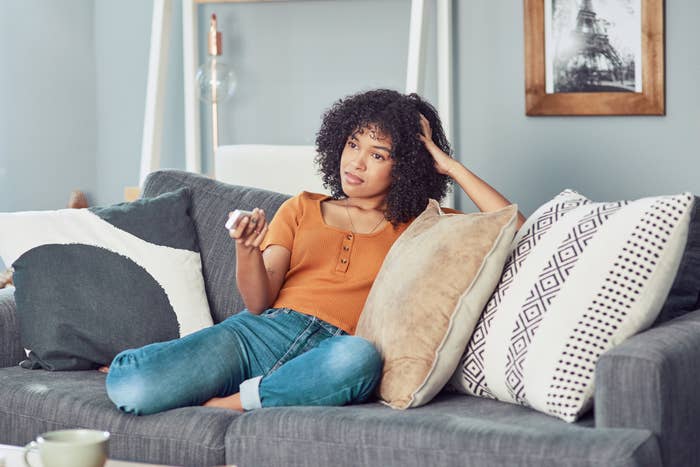 A woman looking bored while watching the TV