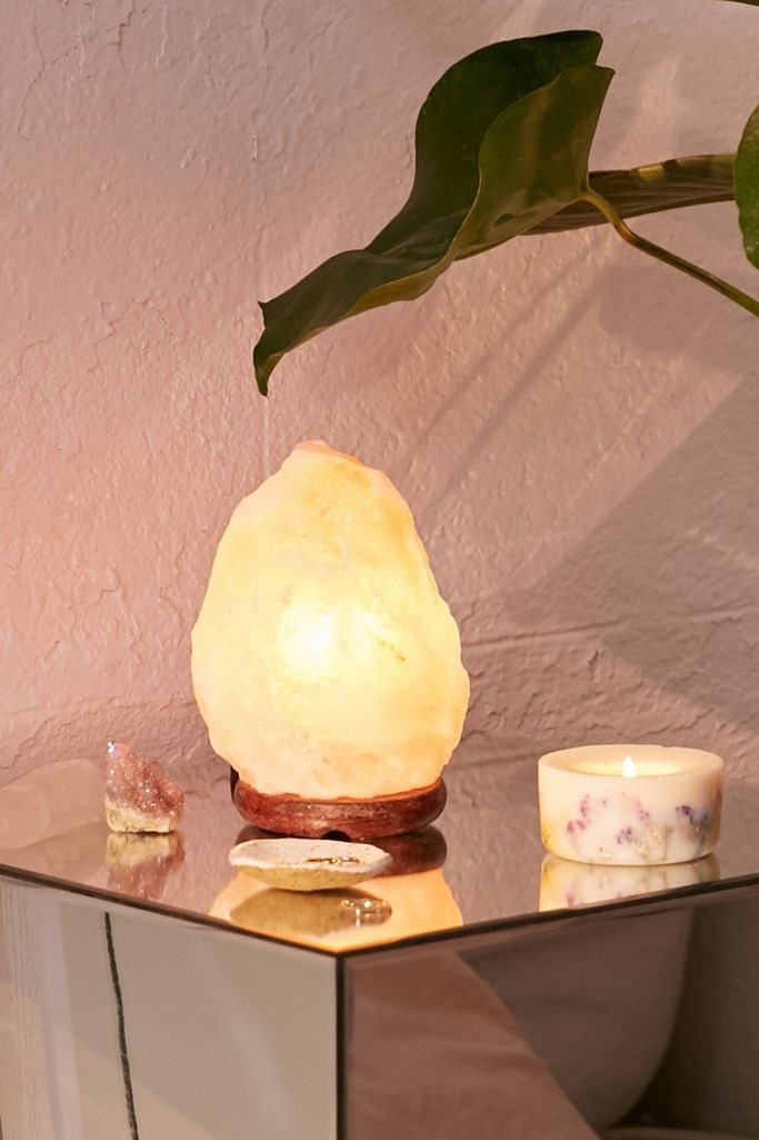illuminated Himalayan salt lamp on table with floral candle