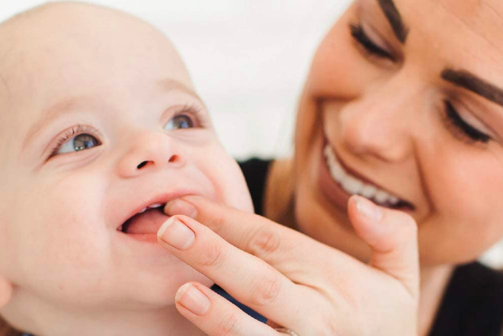 Person rubbing gel onto baby&#x27;s gums 