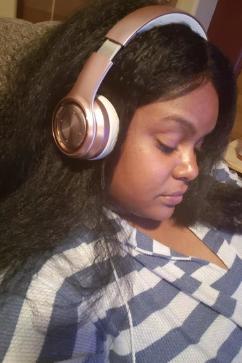 A reviewer wearing the over-ear headphones
