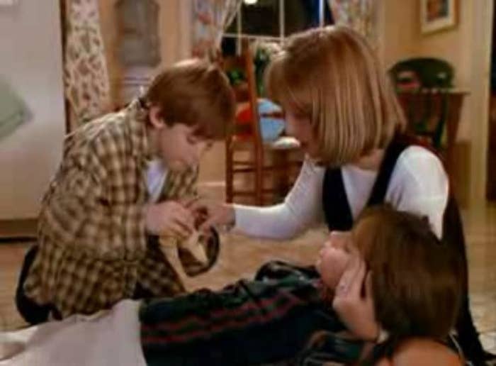 A boy and girl feed a banana to a sick boy