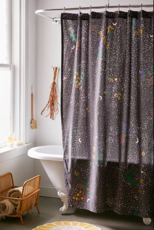 a charcoal shower curtain with white polka dots and a moon and floral print pattern