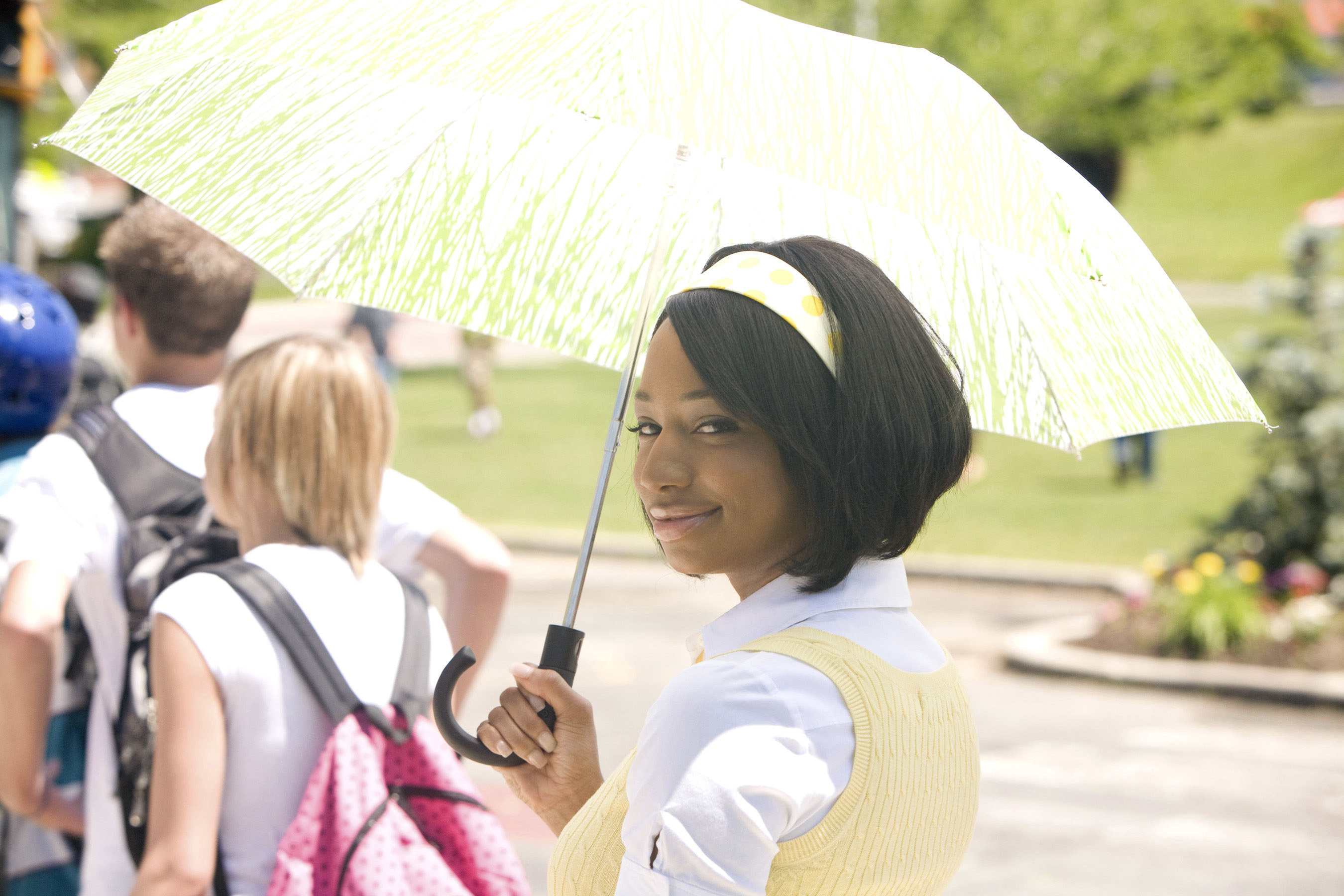 Taylor wearing a light yellow headband and holding a yellow umbrella