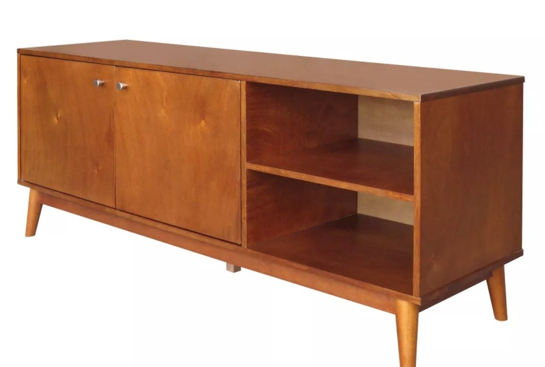 A mid-century modern wooden TV stand with two open shelves on the right and a cabinet on the left